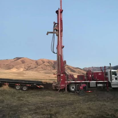 Red drilling rig with mountain backdrop