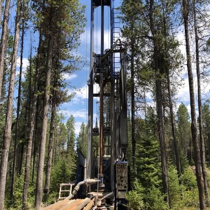 Tall drilling rig among forest trees